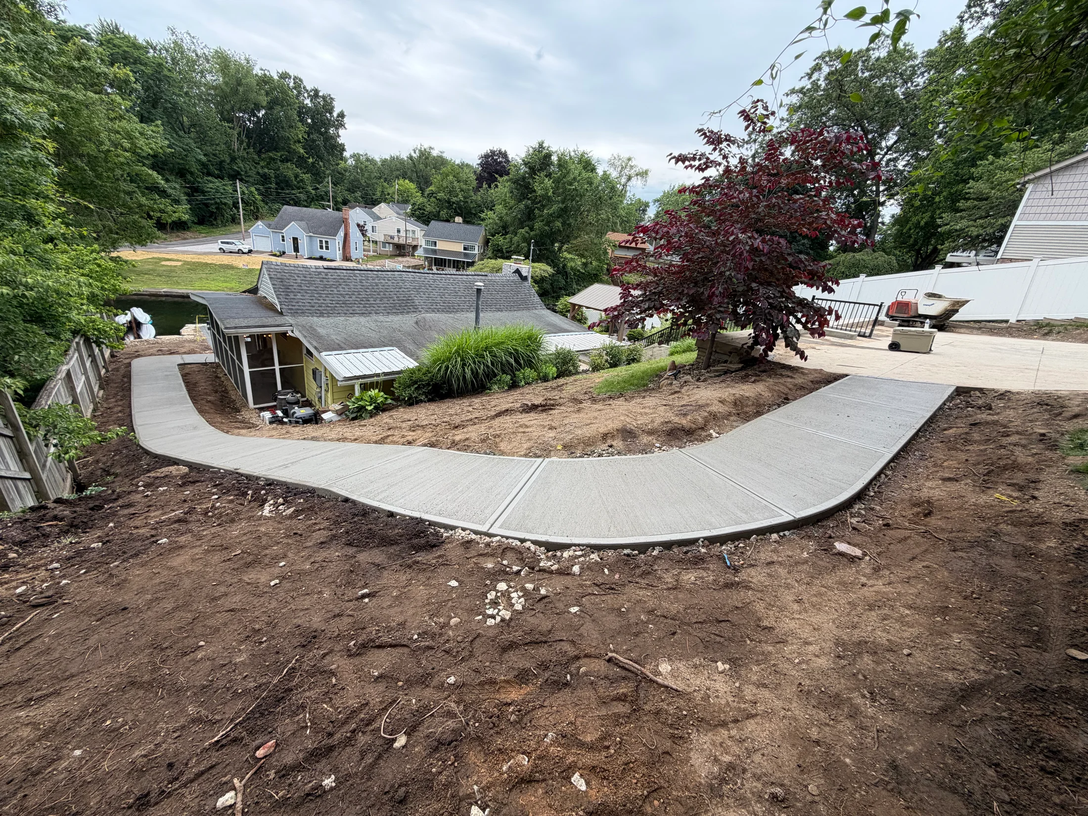 A curved concrete walkway following the slope around the home.