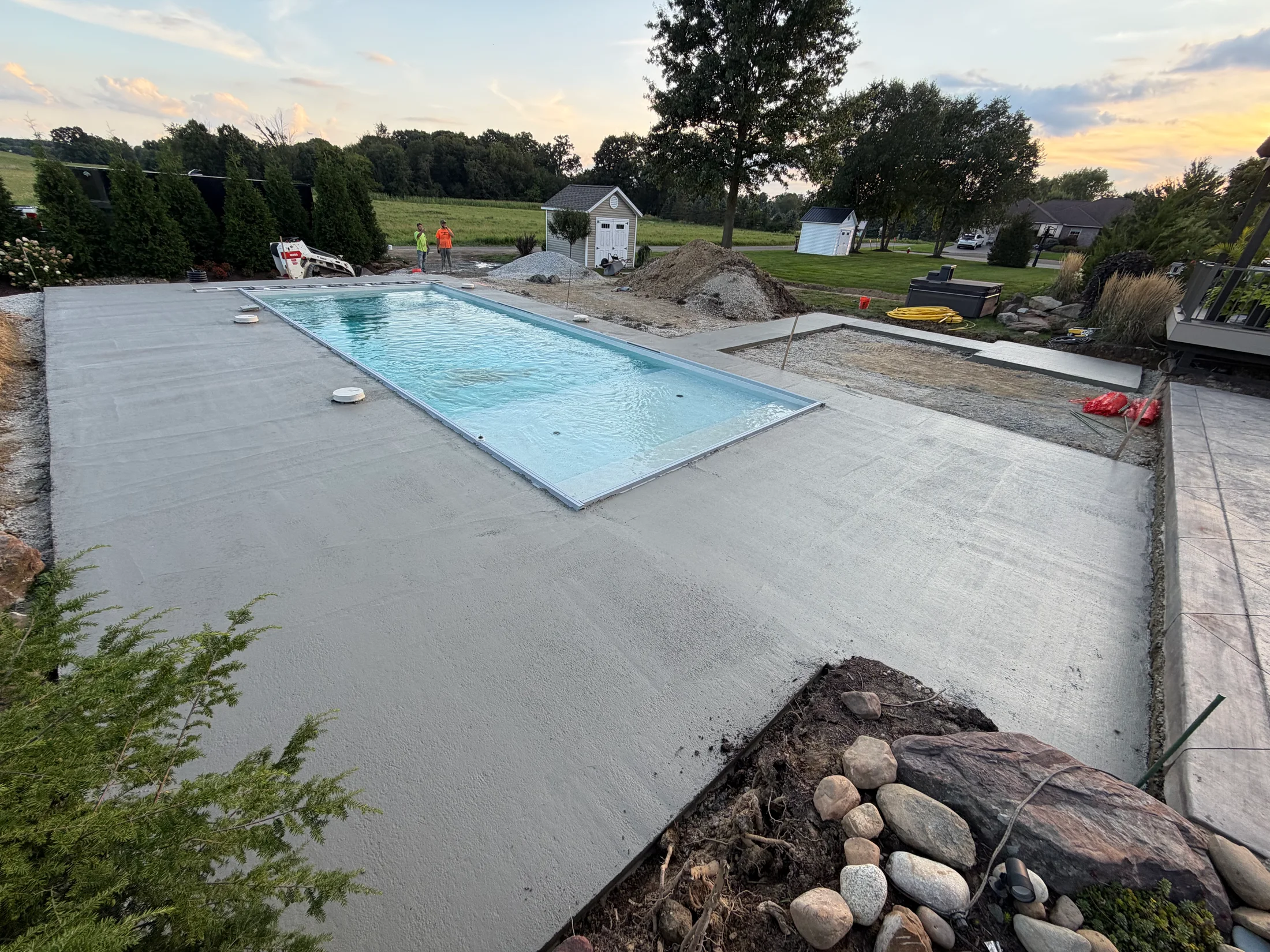 Concrete surround beside a rectangular backyard pool.